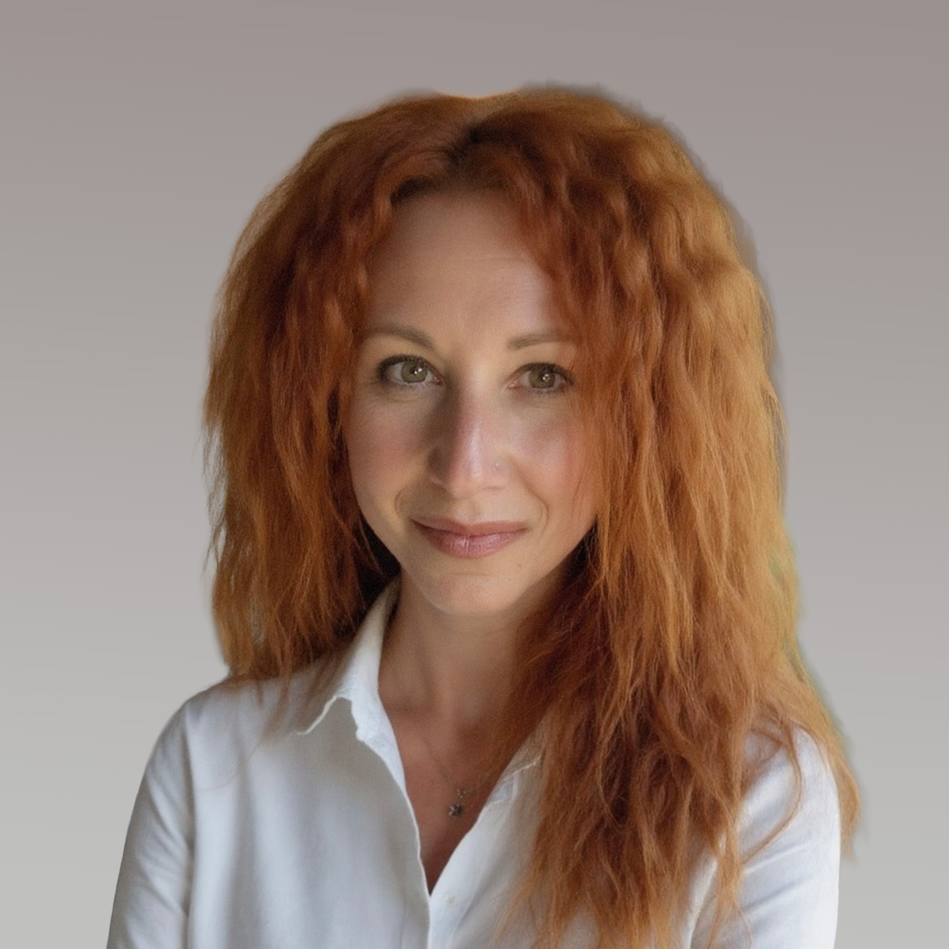 A woman with long, wavy red hair wearing a white collared shirt smiles softly against a neutral gray background.